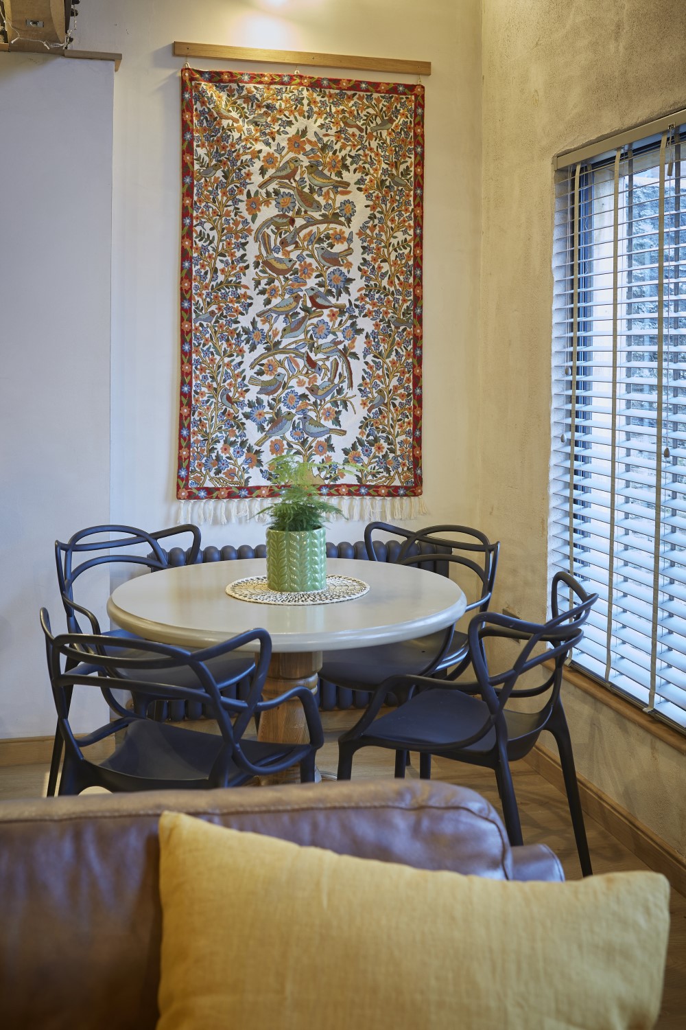 The dining table and chairs with wall tapestry and window to the garden